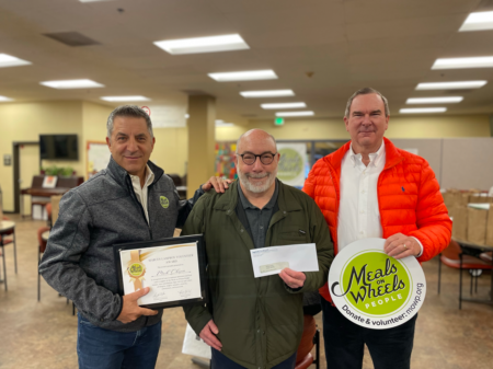 Meals on Wheels People board member Marcus Lampros (left) and donor Peter Northrup (right) surprise volunteer Mark Chapin (center) at the MLK Center.